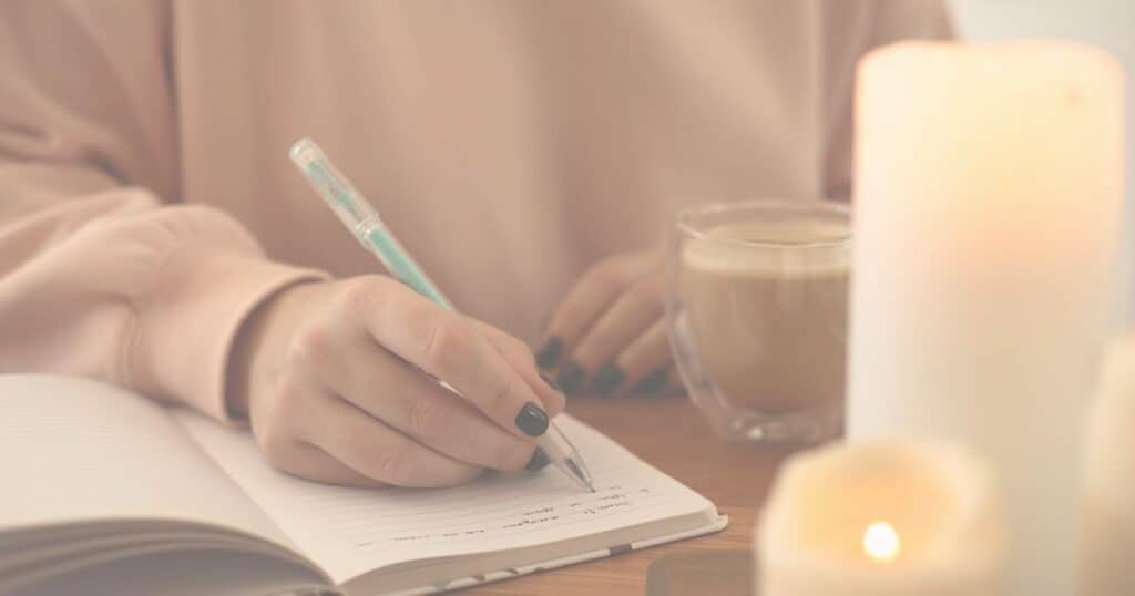 women writing in reading journal with coffee and candles